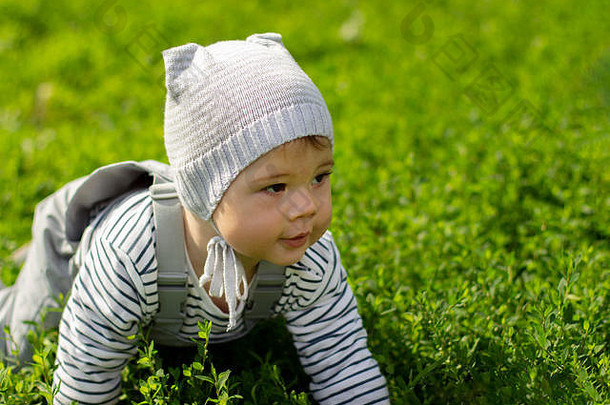 婴儿女孩男孩爬行绿色草坪上肖像孩子特写镜头婴儿学习爬灰色的衣服他防水工作服条纹