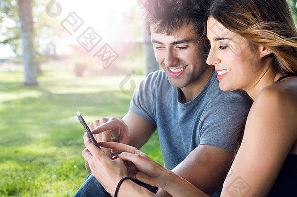 快乐年轻的夫妇智能手机公园