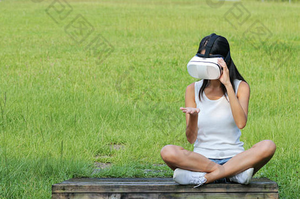 女人看虚拟现实设备坐着公园