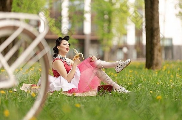 女孩粉红色的衣服发型风格销坐在草野餐草坪上公园阳光明媚的一天复古的风格照片