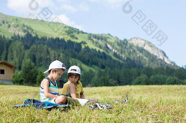可爱的孩子们阅读书草坪上瑞士阿尔卑斯山脉夏季