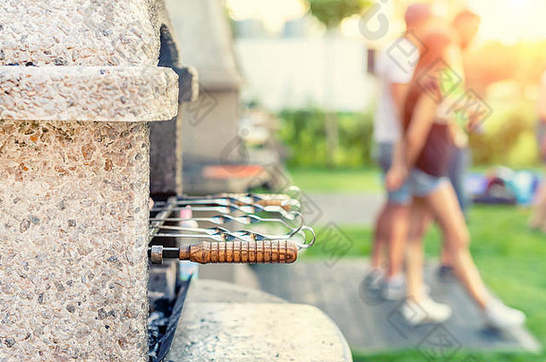 户外石头炉子烧烤串公司朋友烧烤聚会，派对公园后院绿色草草坪上火盆人