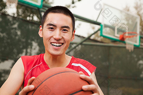 年轻的男人。坐着篮球篮球法院肖像