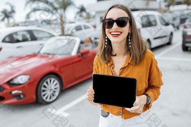 肖像快乐的年轻的女人持有数字平板电脑黑色的屏幕复制粘贴站车停车在户外
