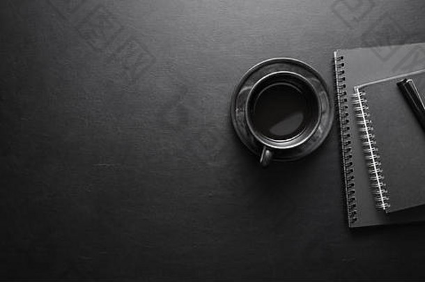 黑暗现代工作场所咖啡杯笔记本黑色的皮革表格背景前视图复制空间