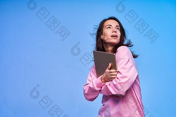 年轻的退出女人持有平板电脑手穿着粉红色的蓝色的背景