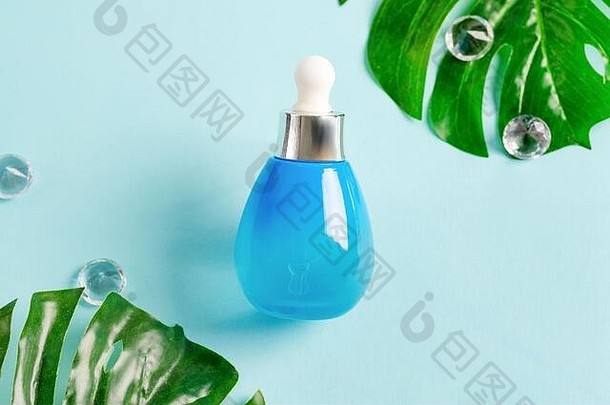 蓝色的瓶化妆品自然至关重要的石油乳液柔和的蓝色的背景热带绿色叶子
