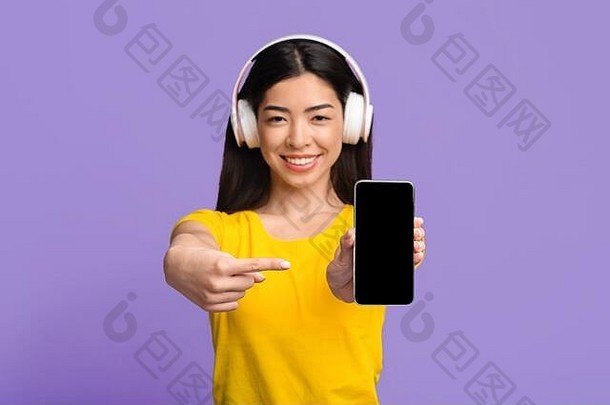 音乐流媒体服务微笑亚洲女人耳机指出黑色的智能手机