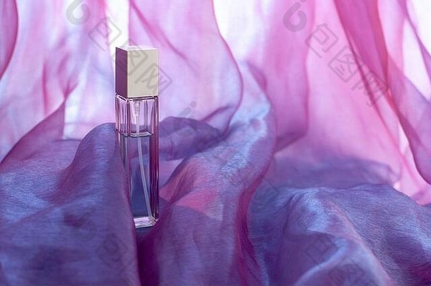 细长的香水瓶美丽的粉红色的皱巴巴的织物模糊背景在上雕琢平面的玻璃瓶空白模拟复制空间有何利