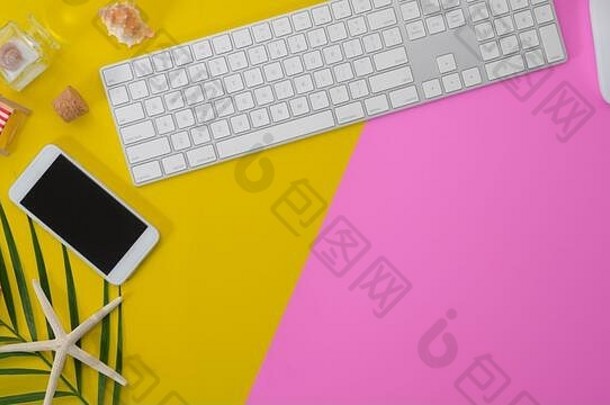 色彩鲜艳的夏天工作空间键盘电脑智能手机粉红色的黄色的桌子上背景