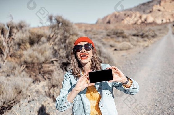 年轻的快乐女人显示智能手机空屏幕复制粘贴旅行沙漠路