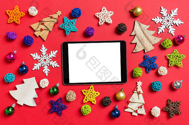 前视图数字平板电脑红色的背景使假期装饰玩具圣诞节点缀概念