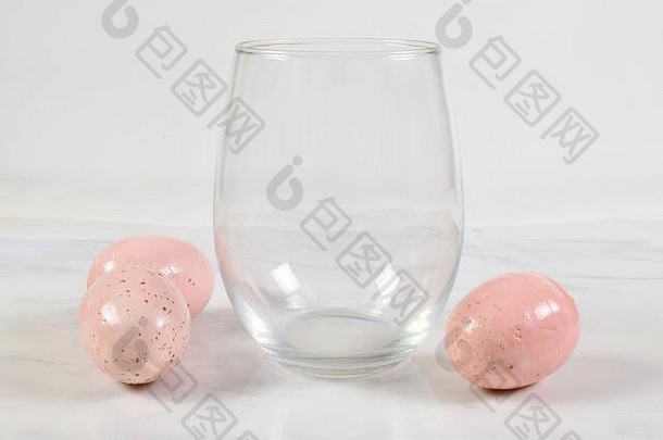 豪华的阀杆葡萄酒杯坐在高高兴兴地白色大理石背景漂亮的粉红色的斑点复活节鸡蛋酒玻璃包围