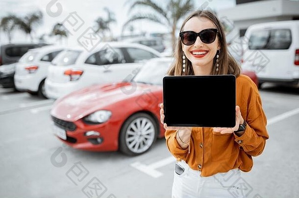 肖像快乐的年轻的女人持有数字平板电脑黑色的屏幕复制粘贴站车停车在户外