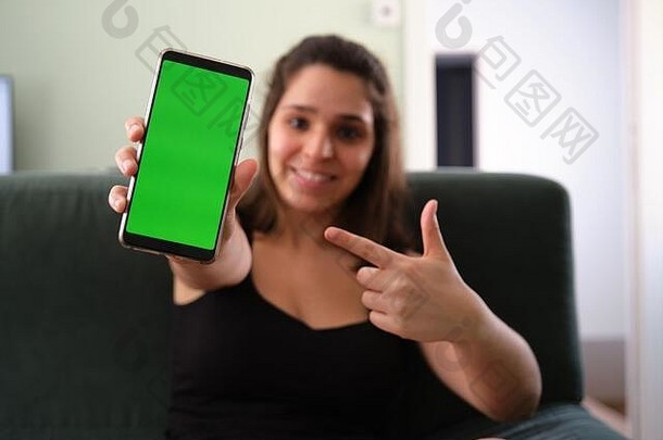 年轻的高加索人女人指出智能<strong>手机</strong>绿色屏幕浓度关键