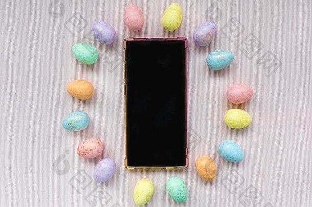 柔和的黄金彩色的鸡蛋装饰智能手机柔和的粉红色的背景复活节庆祝活动概念前视图平躺模拟复制空间