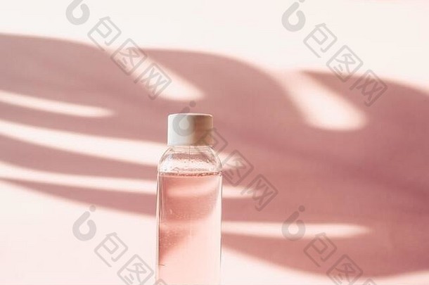 塑料瓶粉红色的玫瑰水柔和的背景热带影子棕榈叶透明的碳粉碳粉滋润净化皮肤胶束水清洗泡沫