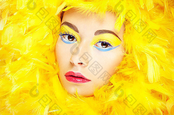 肖像美丽的女孩黄色的羽毛完美的化妆时尚照片