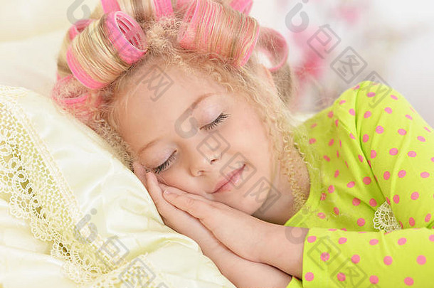 可爱的女孩粉红色的卷发器睡觉