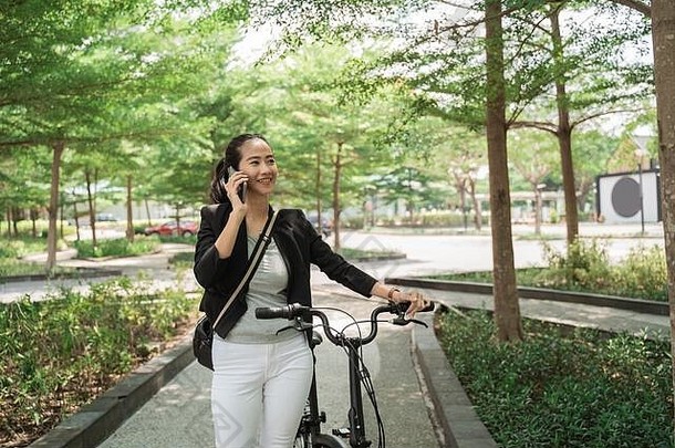 微笑工作女人走折叠自行车接收电话调用