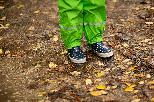 低部分孩子绿色防水裤子橡胶靴子站湿泥泞的地面森林下降秋天叶子多雨的