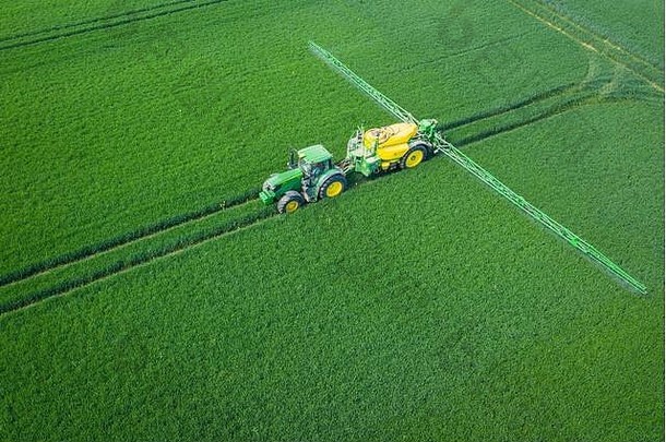 绿色字段空中视图拖拉机喷涂化学物质大绿色场农业春天背景