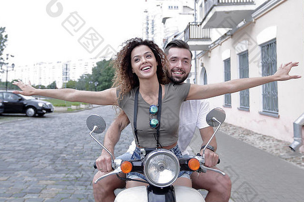 美丽的年轻的夫妇微笑骑踏板车