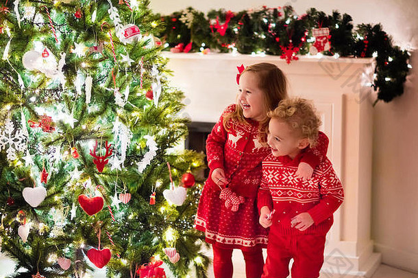 快乐孩子们匹配红色的针织毛衣装修圣诞节树美丽的生活房间传统的火的地方