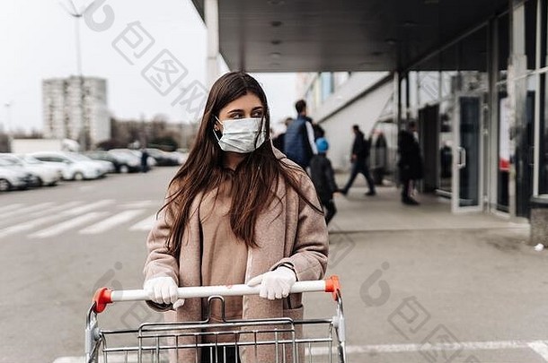 年轻的女人穿保护脸面具冠状病毒法律顾问推购物车