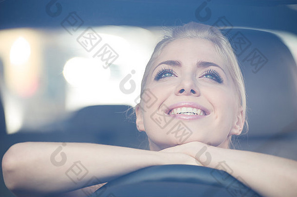 微笑年轻的女人靠车操舵轮