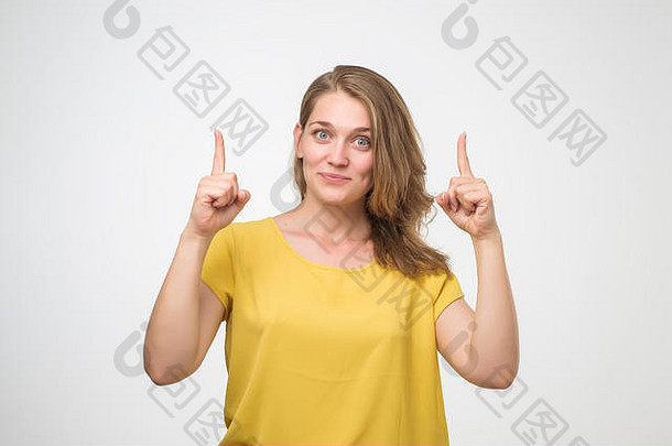 微笑欧洲女人黄色的衬衫指出手指孤立的工作室肖像