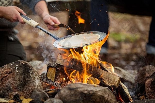 男人。女人使煎饼篝火森林海岸湖使火烧烤快乐夫妇探索芬兰斯堪的那维亚景观