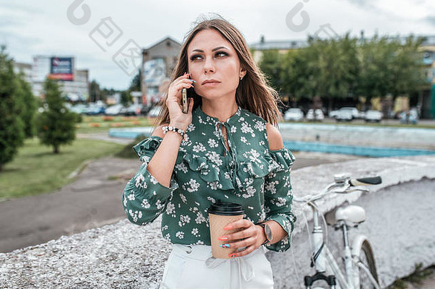 女人夏天城<strong>市调</strong>用电话手杯咖啡茶背景树自行车业务调用业务女孩工作