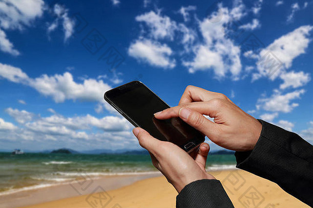 女人手持有触摸屏幕聪明的电话<strong>手机</strong>模糊摘要蓝色的多云的天空海滩背景
