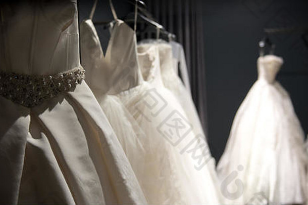 选择手工制作的白色婚礼礼服挂铁路黑暗的房间部分照亮光