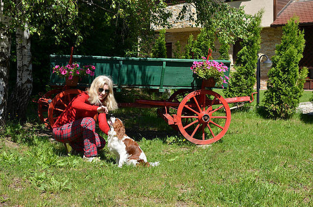 女人玩狗花园前面老式的木绿色车红色的轮子