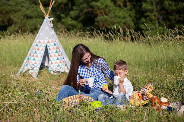 妈妈。年轻的儿子吃野餐自然旅行