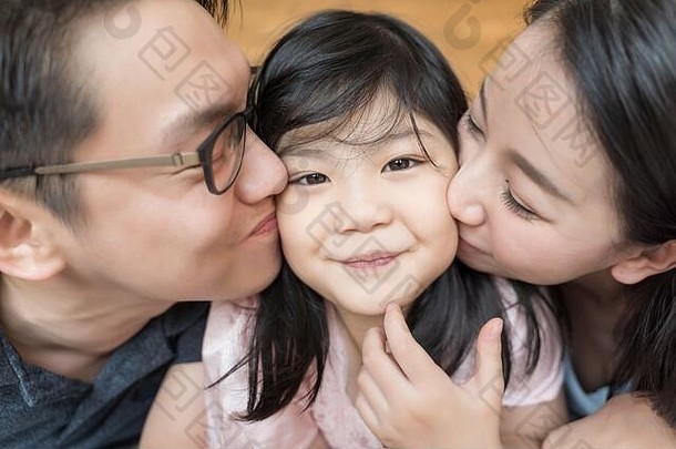 亚洲父母接吻女儿脸颊家庭肖像