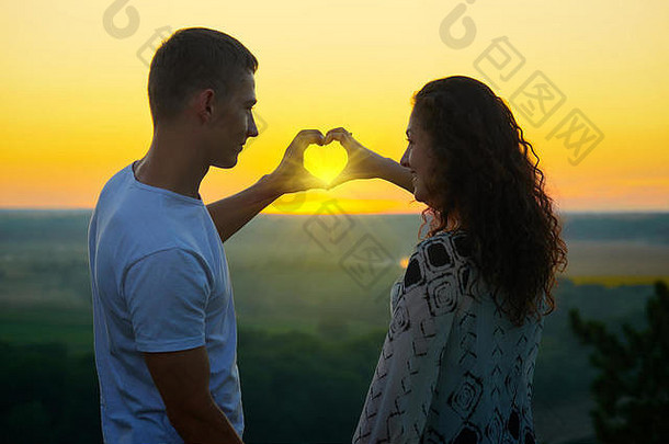 浪漫的夫妇日落使心形状手射线太阳发光手美丽的景观明亮的叶尔