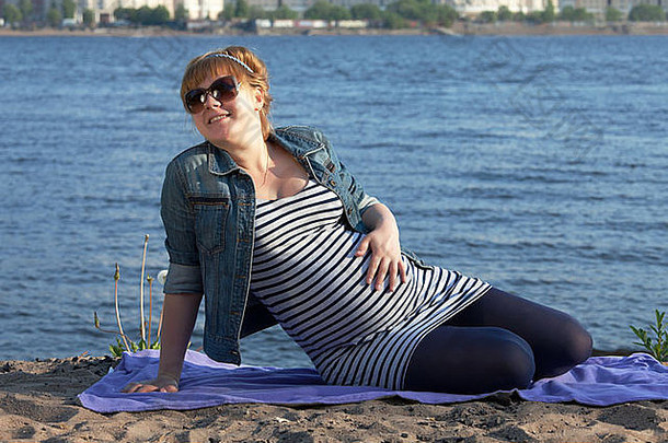 怀孕了女人坐着河海岸