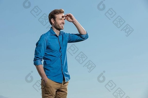 一边视图迷人的休闲男人。穿蓝色的衬衫站手口袋里保护眼睛太阳outisde