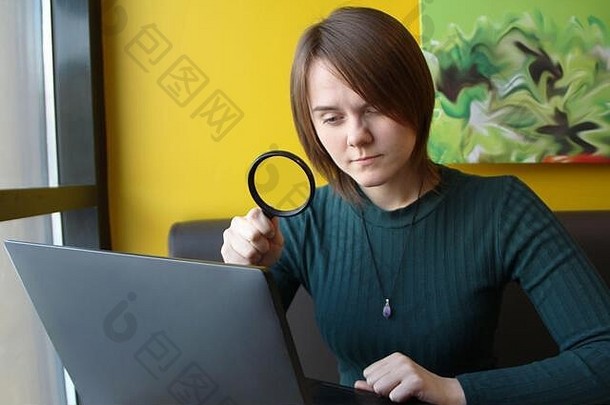 年轻的美丽的女孩欧洲外观蓝色的夹克坐着咖啡馆工作移动PC沙发上背景黄色的墙电脑显示放大镜布局设计的地方文本