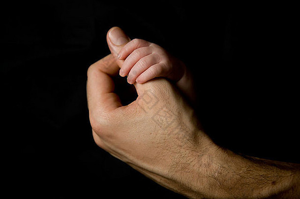 新生儿婴儿手持有父亲的拇指