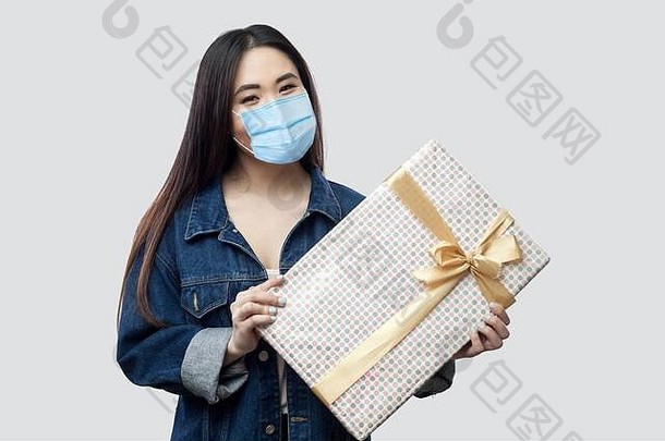 肖像善良有吸引力的年轻的亚洲女人医疗面具蓝色的牛仔布夹克站持有现在微笑相机