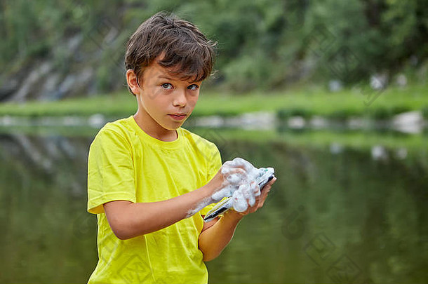 男孩洗移动电话肥皂站河岸孩子毁了父母的小工具润湿