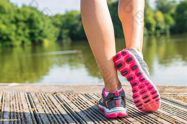 女人跑步者穿体育鞋子甲板湖
