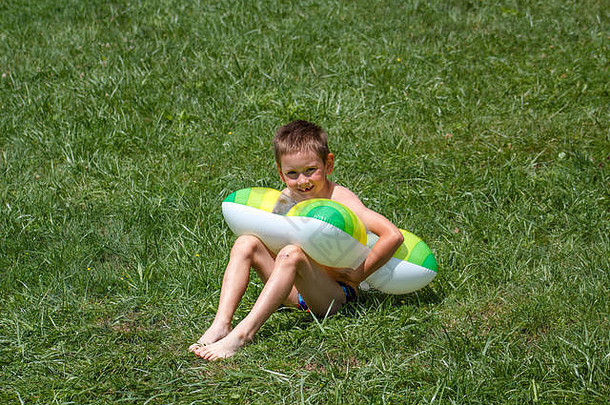 男孩坐着游泳环草