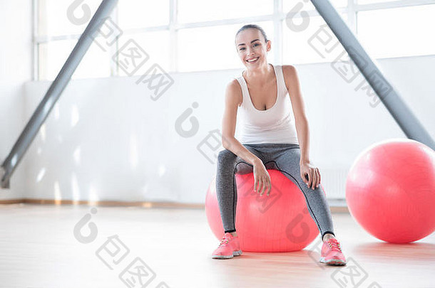 很高兴建女人坐着粉红色的健身球