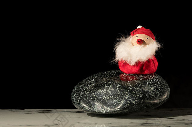 小手工制作的小雕像圣诞老人老人站抛光石头黑色的背景