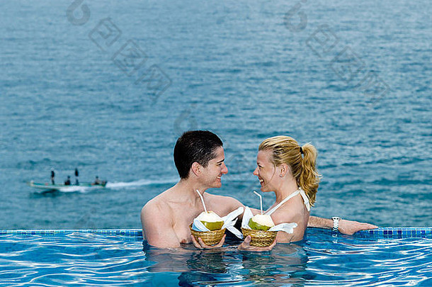 美丽的高加索人夫妇享受假期游泳池<strong>海边</strong>喝椰子牛奶